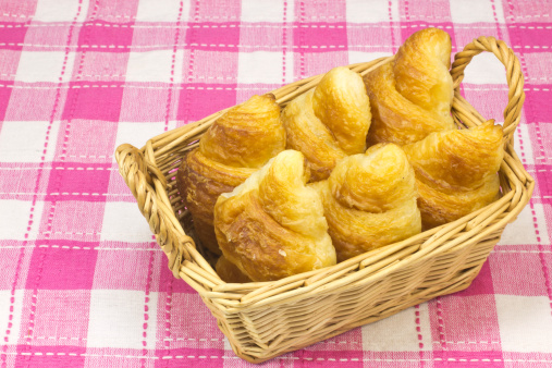 Sei croissant in un cestino su una tovaglia a quadri
