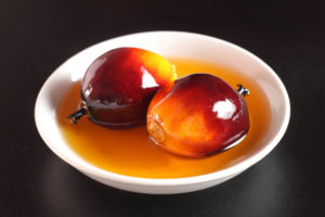 Due frutti della palma da olio in una ciotola con olio di palma