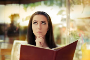 Donna pensierosa davanti a un menu al ristorante