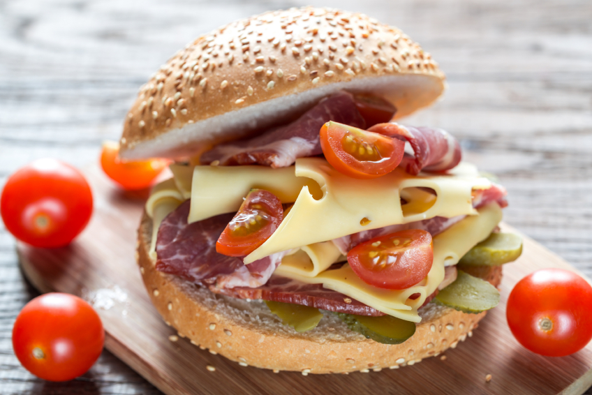 Panino con prosciutto, formaggio a fette e pomodorini su un tagliere