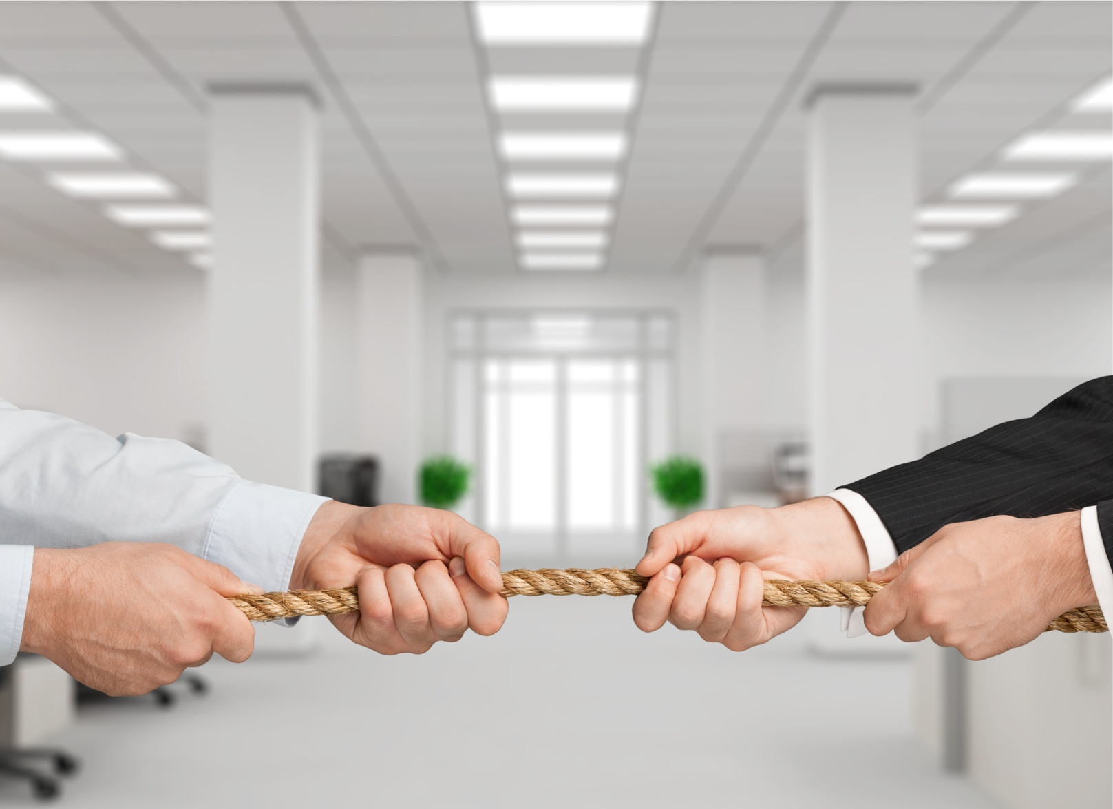 Due uomini fanno tiro alla fune in ufficio; concept: conflitto di interessi