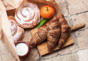 Corissant ed ensaimada con un mandarino e una ciotolina di yogurt, latte o crema