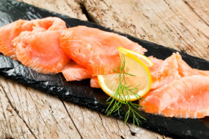 fette di salmone affumicato con limone e aneto su un vassoio di ardesia