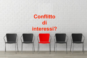 Sedia rossa in mezzo a sedie nero; concept: conflitto di interessi