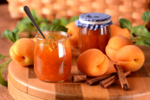 Due vasetti di marmellata di albicocche con albicocche su un tavolo; concept: marmellate