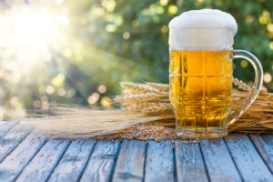 birra, spighe e orzo di mais su un vecchio tavolo sotto i raggi del sole