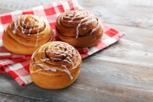 Cinnamon rolls con glassa su un tovagliolo a quadretti; concept: brioche, merendine