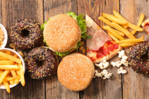 Alimenti poco sani: patatine fritte, hamburger da fast food, pizza, pop corn, donut al cioccolato