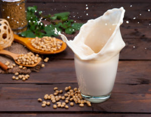 Schizzo di latte di soia con fagioli su legno