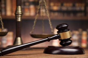 Tema del diritto, mazza del giudice, scrivania in legno, libri, tribunale, sentenza antitrust