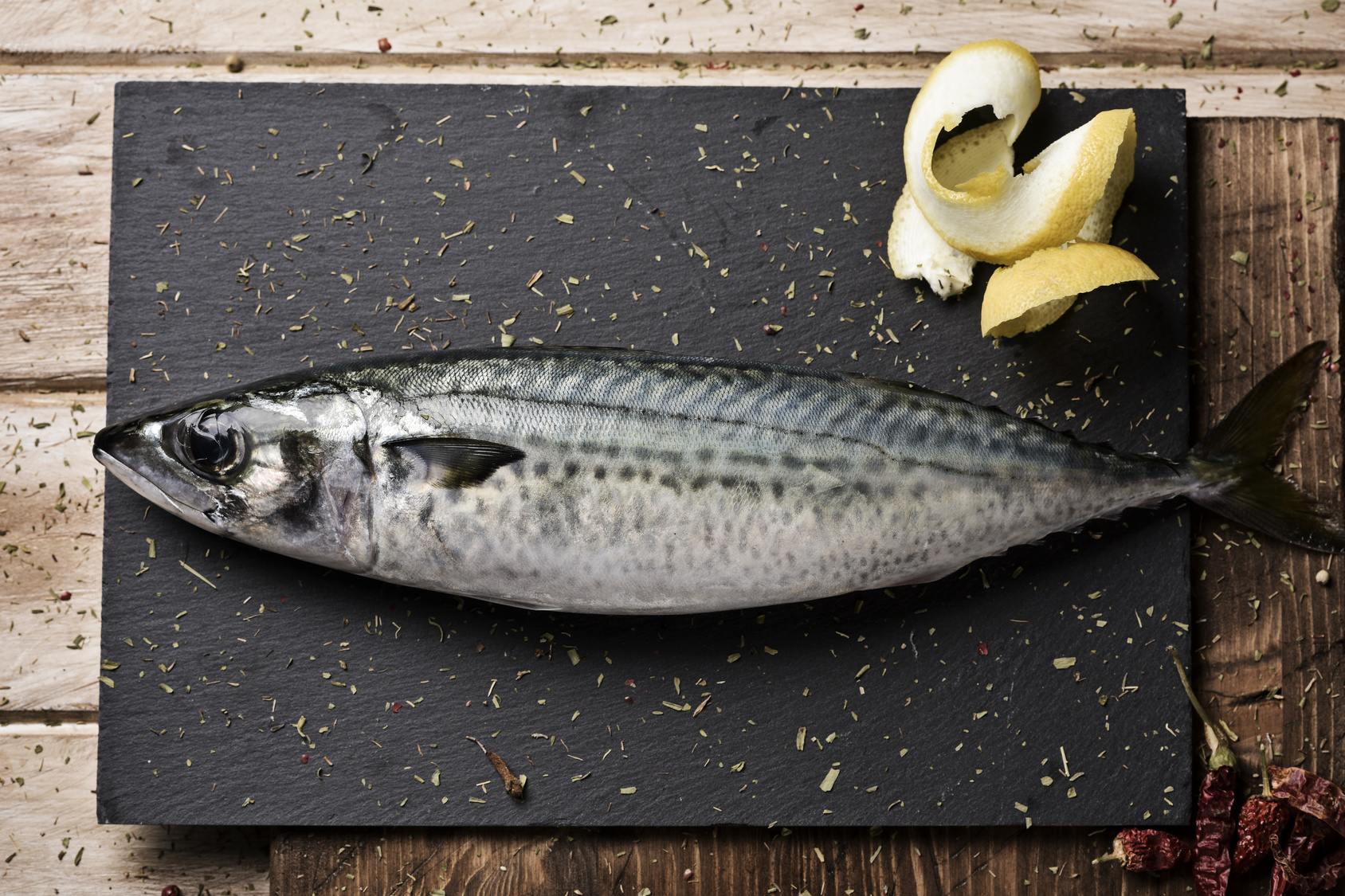 Uno sgombro su un tagliere di ardesia con fette di limone; concept: pesce azzurro