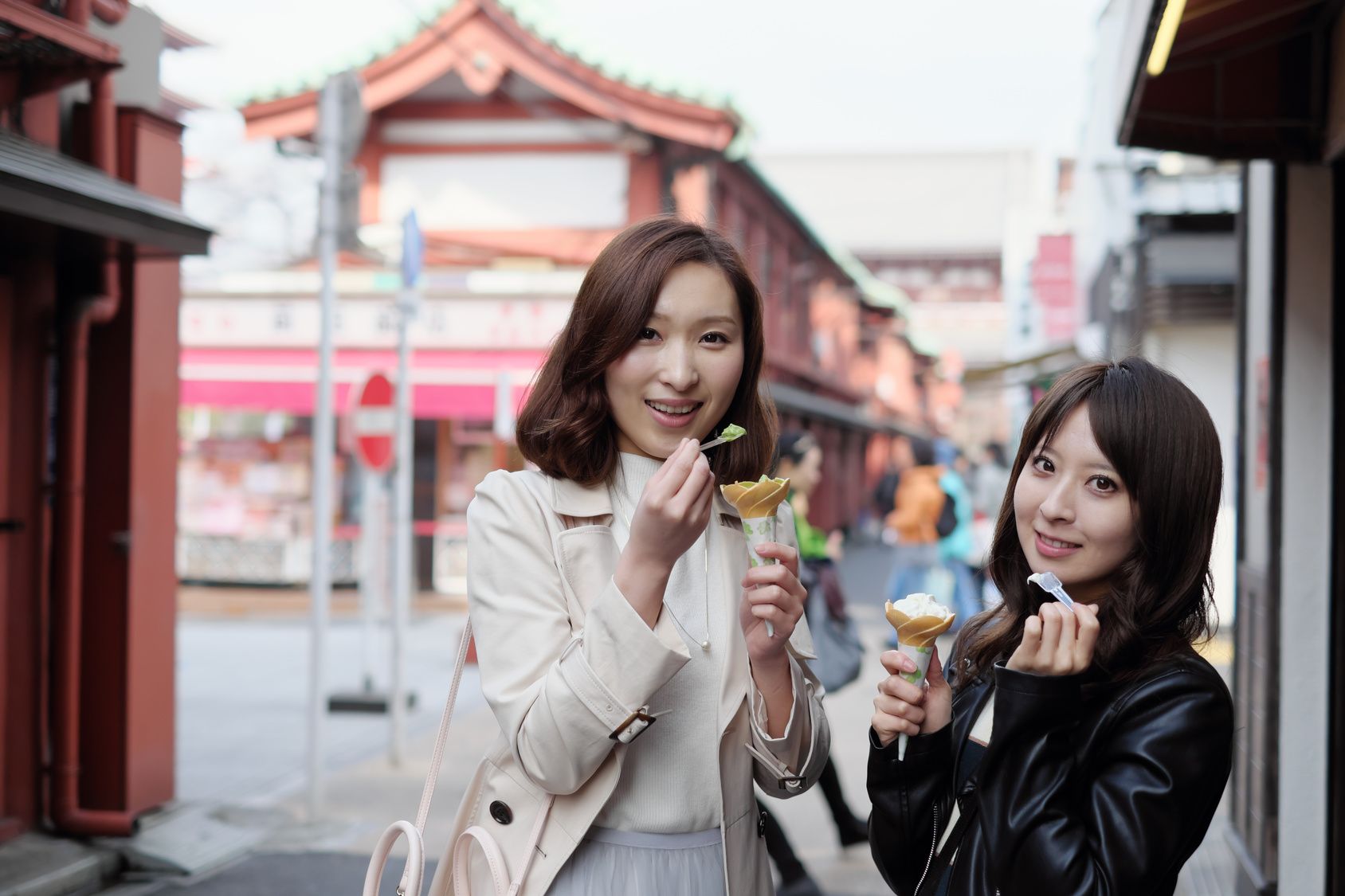 Due donne asiatiche mangiano un gelato per strada; concept: Cina, Asia