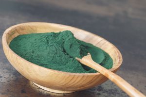 Ciotola e cucchiaio di legno con polvere di spirulina