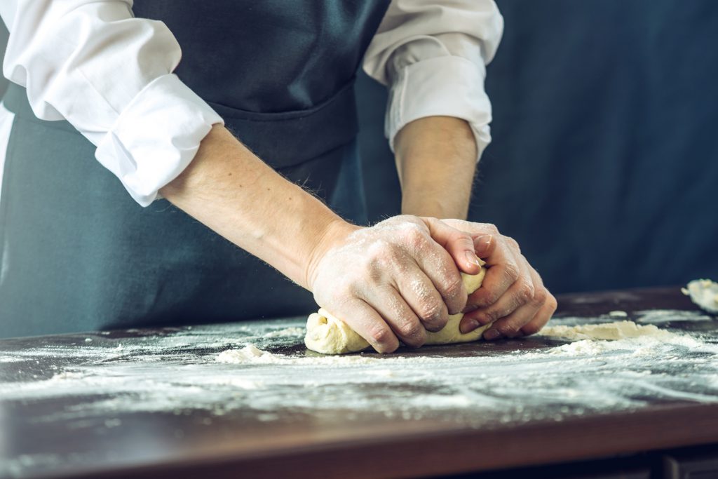 pizza, The chef in black apron makes pizza dough with your hands on the table