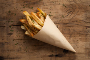 Patate fritte avvolte in un cono di carta paglia; concept: acrilammide