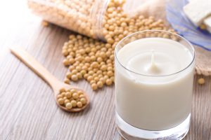 Bicchiere di bevanda di soia con fagioli di soia sullo sfondo