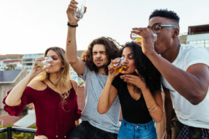 Gruppo di giovani ragazzi e ragazze bevono birra durante una festa all'aperto; concept: alcol, bevande alcoliche