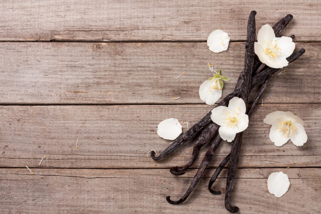 Vanilla sticks with flower and leaf on a old wooden background with copy space for your text. Top view