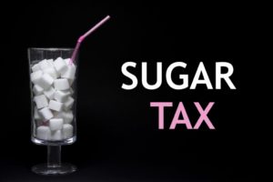 Bicchiere con cannuccia pieno di cubetti di zucchero cibo la scritta sugar tax; concept: bevande zuccherate