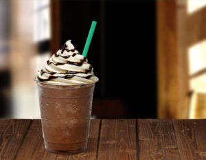 Frappuccino in takeaway cup on wooden table isolated on cafe background