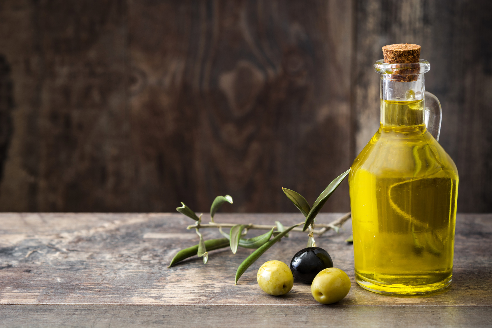 Bottiglia di olio extravergine di oliva accanto a ramoscello e olive