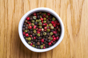 White bowl with pepper mix. Various pepper served in white bowl on wooden background.