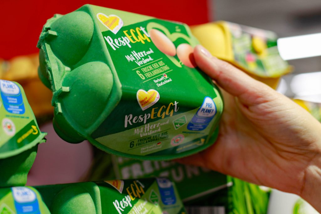 Una mano preleva un cartone di uova Respeggt da uno scaffale di un supermercato Rewe