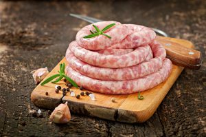 Salsiccia fresca cruda su un vecchio sfondo di legno carne proteine grassi insaccati