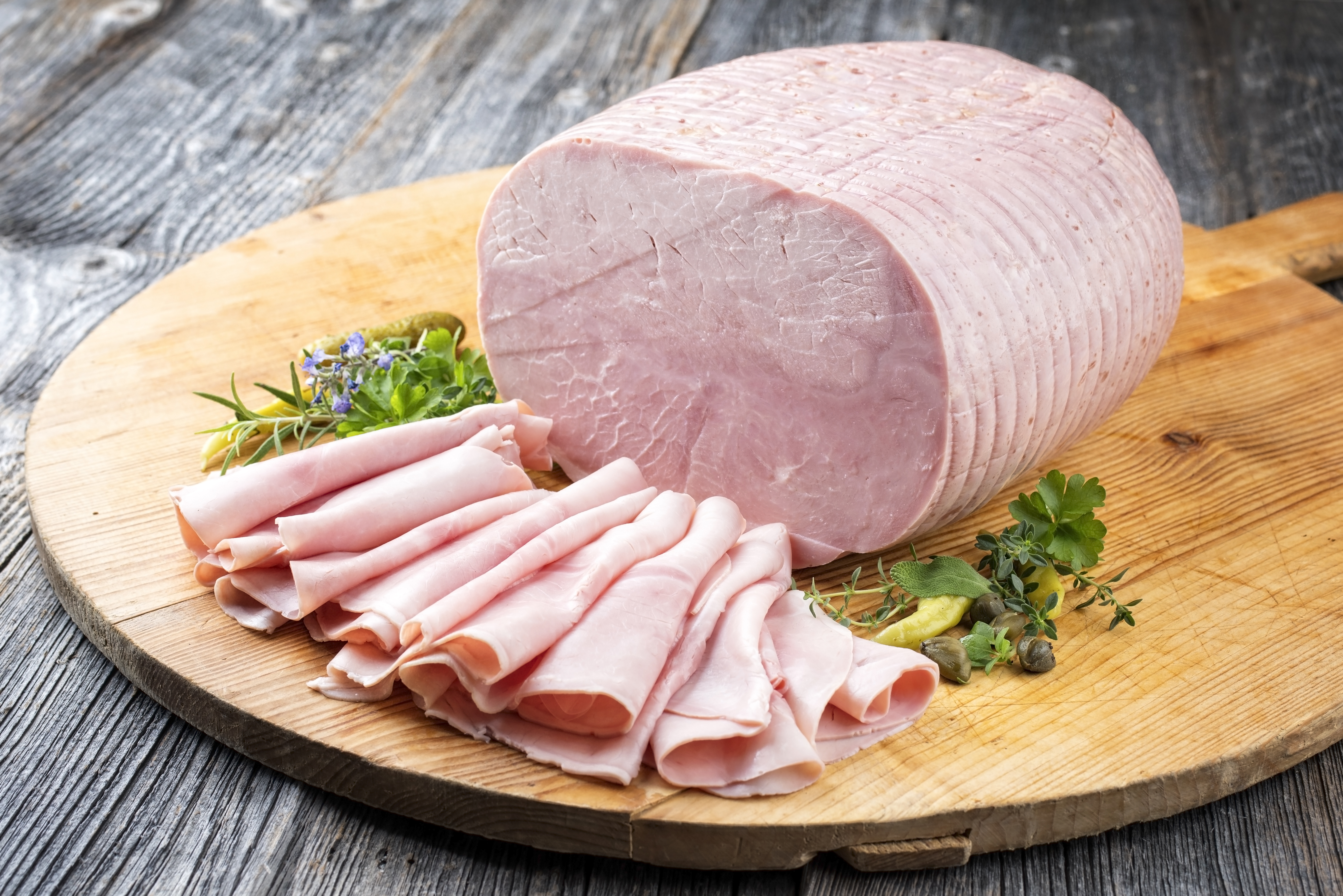 Forma di prosciutto cotto e prosciutto cotto affettato su un tagliere di legno