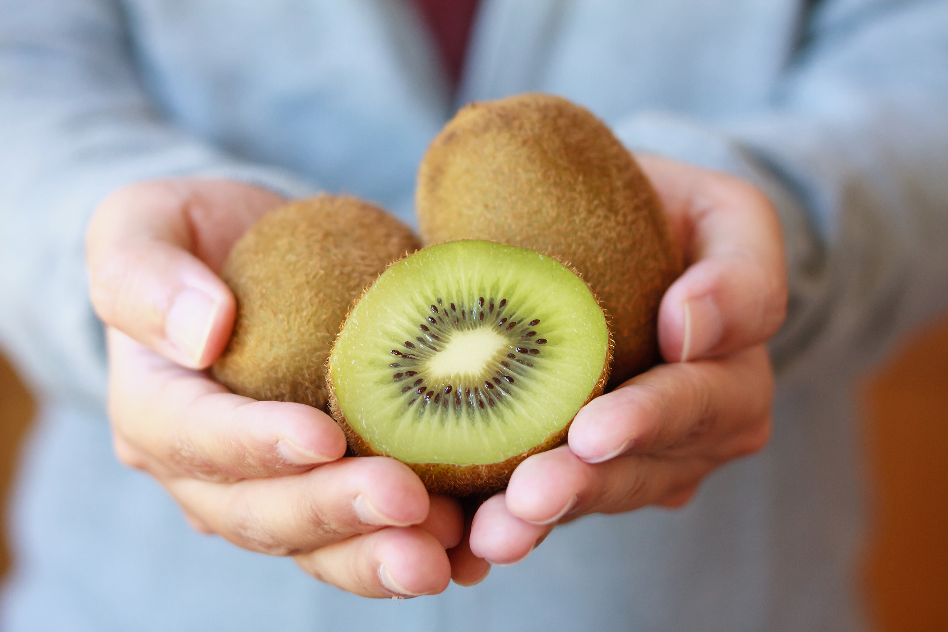 Una persona tiene in mano alcuni kiwi