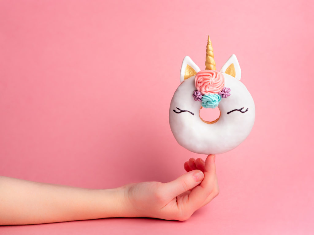 Unicorn donut on forefinger, copy space