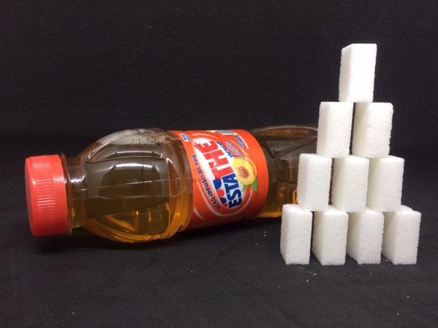 Estathé alla pesca Ferrero accanto a piramide di zollette di zucchero