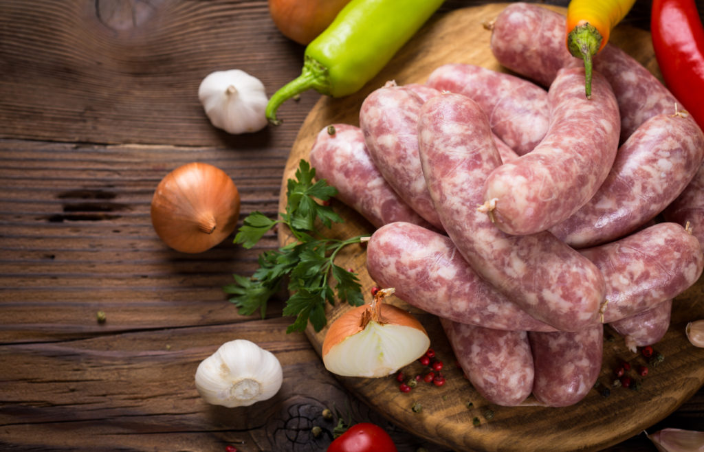 Raw sausages on the wooden board