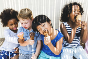 Quattro bambini mangiano il gelato su sfondo parete bianca