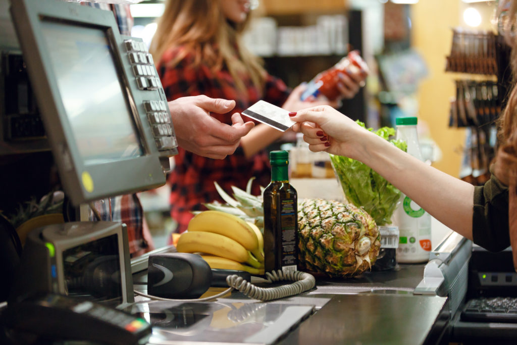 Una cassiera porge una carta di credito a una persona; concept: cassa del supermercato