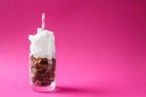 Bicchiere di bibita zuccherata riprodotto con zollette di zucchero bianche e di canna