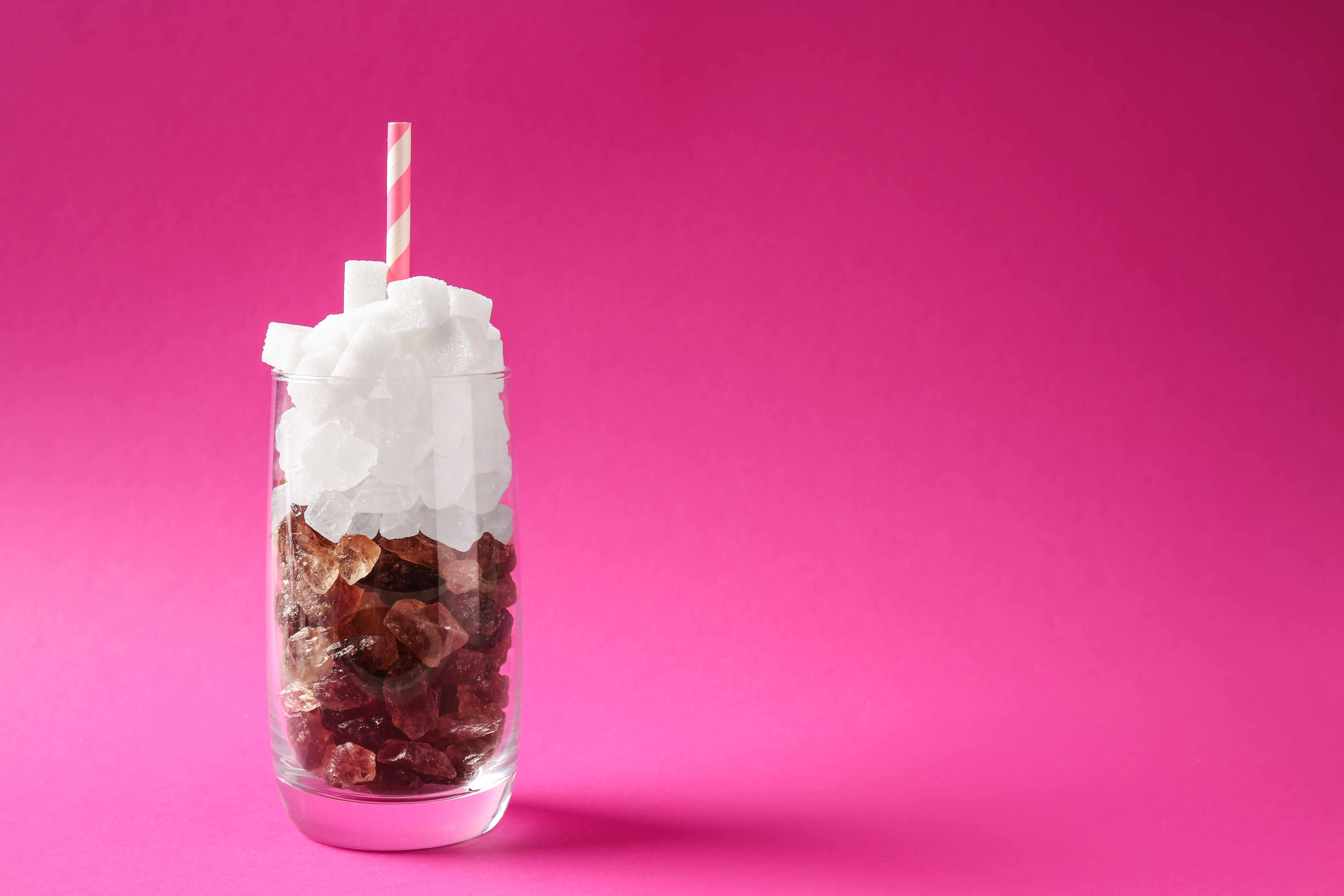 Bicchiere di bibita zuccherata riprodotto con zollette di zucchero bianche e di canna