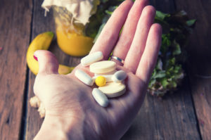 Una manciata di compresse e capsule su una mano; concept: integratori alimentari, vitamine