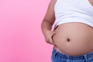 Bambino sovrappeso con maglietta sollevata per mostrare la pancia