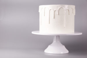 Simple white cake with glaze on a gray background.