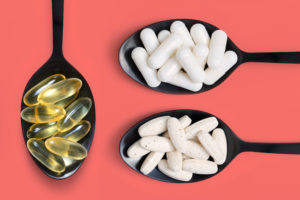 Tre cucchiai neri con capsule, compresse e capsule molli di integratori o farmaci; concept: integratore, farmaci, probiotici, antibiotici