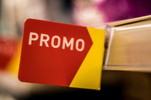 Un cartello promozionale rosso e giallo sullo scaffale di un supermercato; concept: offerte, promozioni, supermercati, prezzi