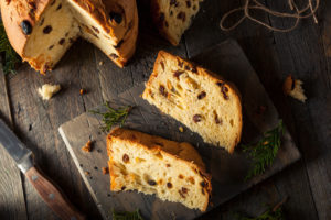 Fette di panettone viste dall'alto su un tagliere, accanto a un panettone tagliato; concept: Natale, panettoni