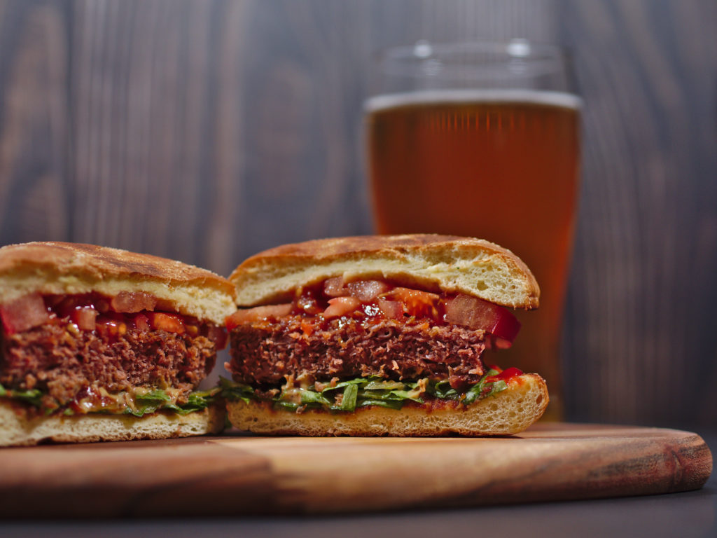 vegan plant based burger served on rustic cutting board with beer