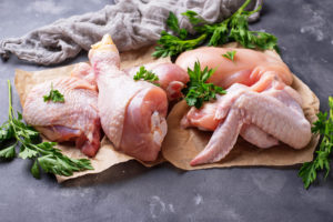 Gallina o pollo crudo porzionato su un pezzo di carta con erbe aromatiche; concept: carne, proteine animali,