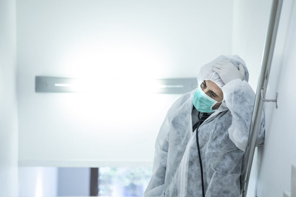 medico in prima linea con mascherina e protezione e disperato e stremato dalla stanchezza