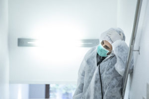 medico in prima linea con mascherina e protezione e disperato e stremato dalla stanchezza