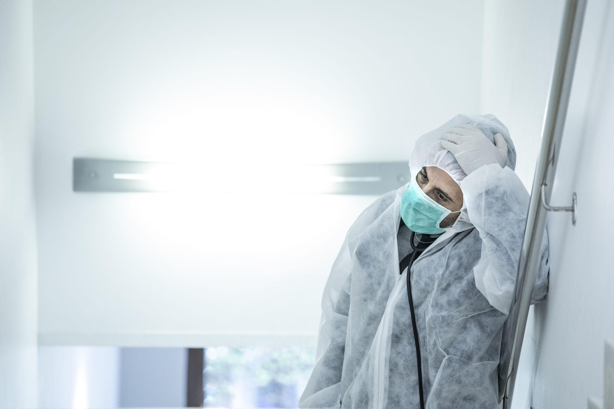 medico in prima linea con mascherina e protezione e disperato e stremato dalla stanchezza