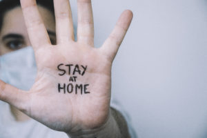 Woman on a side with his hand facing in front with the sentence "stay at home" written on the palm of her hand. Coronavirus concept.