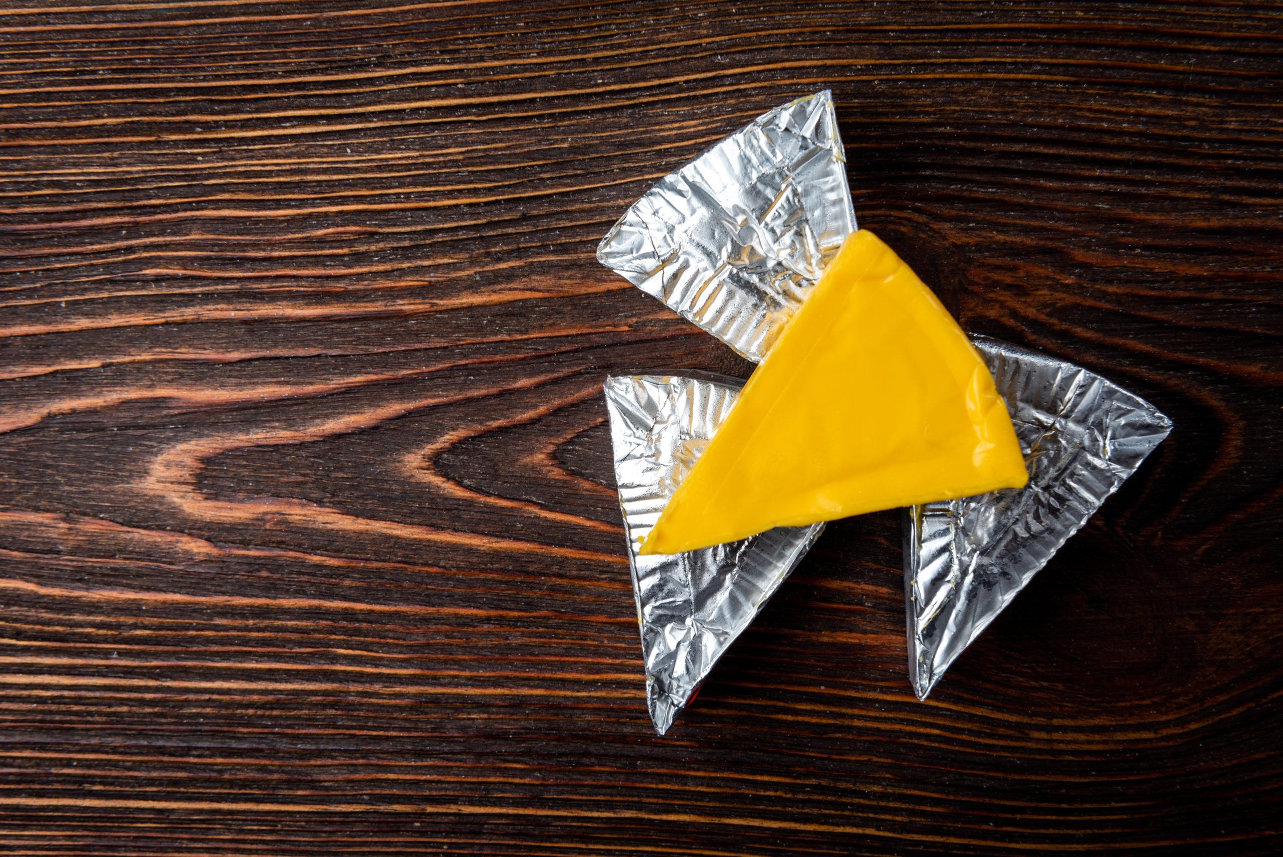 Formaggio formaggino alimenti processati su sfondo di legno scuro.